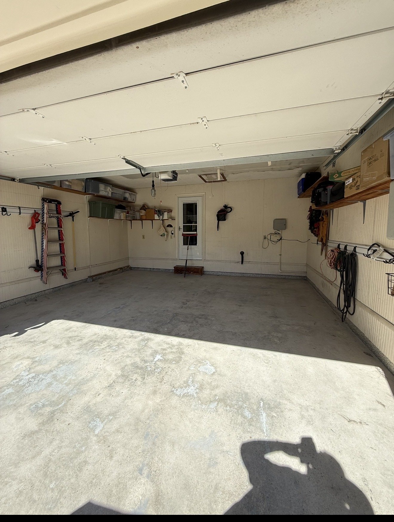 Bare, stained concrete garage floor before coating, seen from the driveway