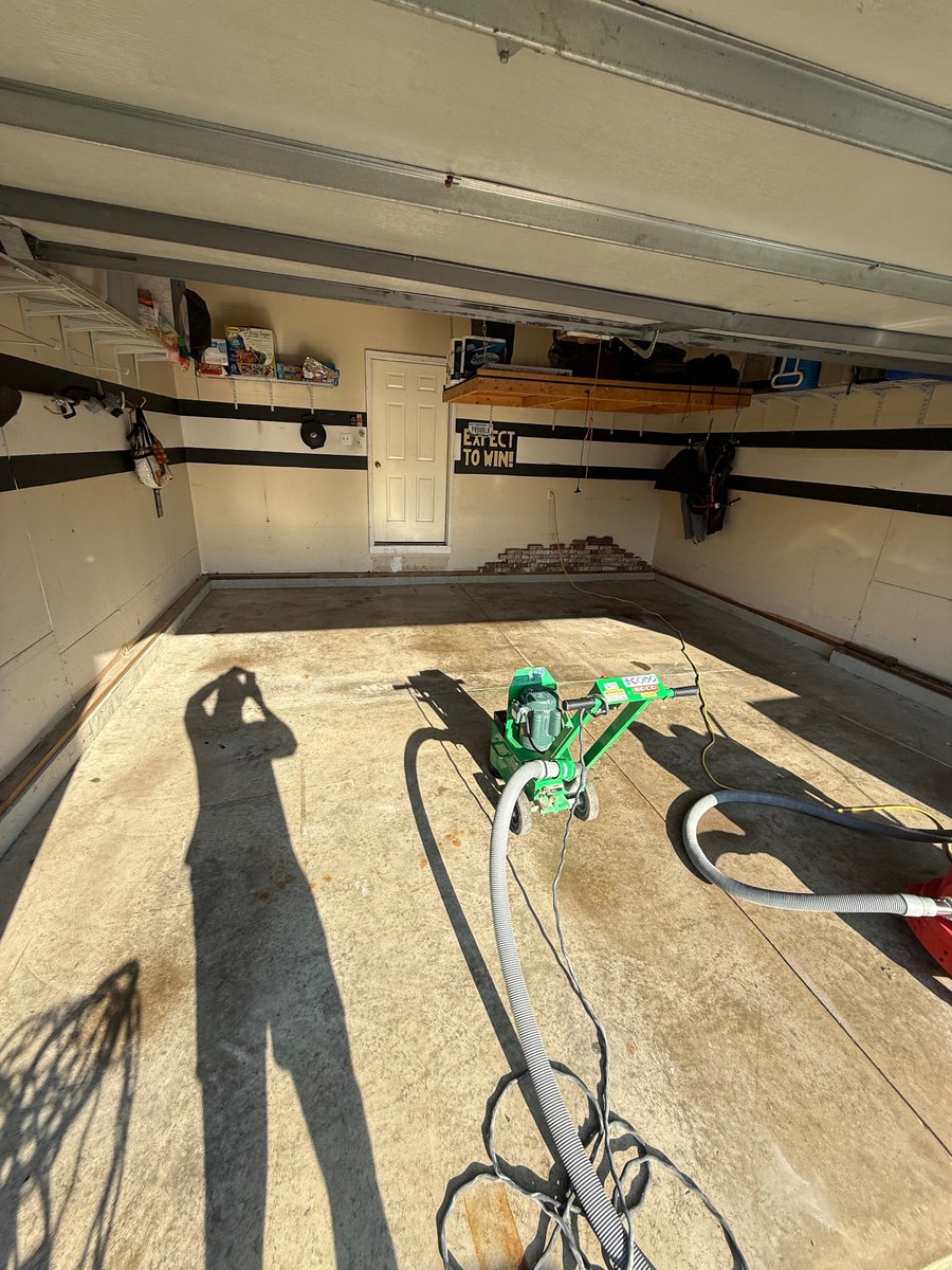 Concrete garage floor before coating with grinding equipment, toward the back wall